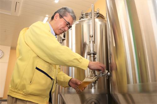 新座クラフトのビールをタンクから注いでいる写真です。